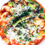 Overhead close-up asparagus and tomato orecchiette pasta soup/stew with wild garlic.