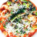 Overhead close-up asparagus and tomato orecchiette pasta soup/stew with wild garlic.