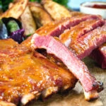 Close-up apricot jam and mustard glazed bacon ribs served with air fryer potato wedges.