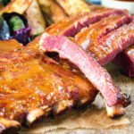 Close-up apricot jam and mustard glazed bacon ribs served with air fryer potato wedges.