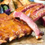 Close-up apricot jam and mustard glazed bacon ribs served with air fryer potato wedges.