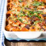 Cheesy baked pasta al forno with a beef, pork and tomato sauce garnished with fresh basil.