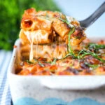 Cheesy baked pasta al forno with a beef, pork and tomato sauce being served from a baking dish.