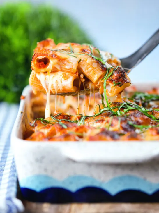 Cheesy baked pasta al forno with a beef, pork and tomato sauce being served from a baking dish.