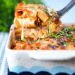 Cheesy baked pasta al forno with a beef, pork and tomato sauce being served from a baking dish.