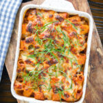 Overhead cheesy baked pasta al forno with a beef, pork and tomato sauce garnished with fresh basil.