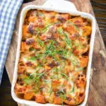 Overhead cheesy baked pasta al forno with a beef, pork and tomato sauce garnished with fresh basil.
