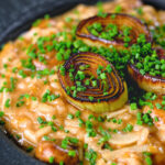 Close-up creamy balsamic leek and mushroom risotto topped with seared leek rings.