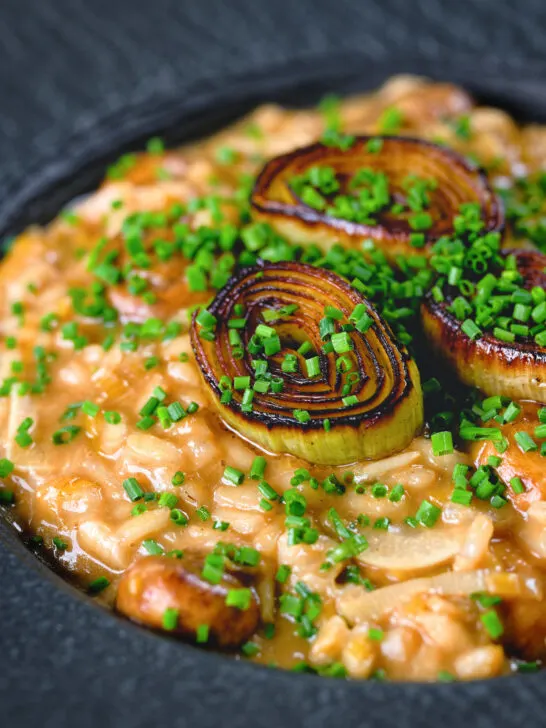 Close-up creamy balsamic leek and mushroom risotto topped with seared leek rings.