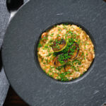 Overhead creamy balsamic leek and mushroom risotto topped with seared leek rings.