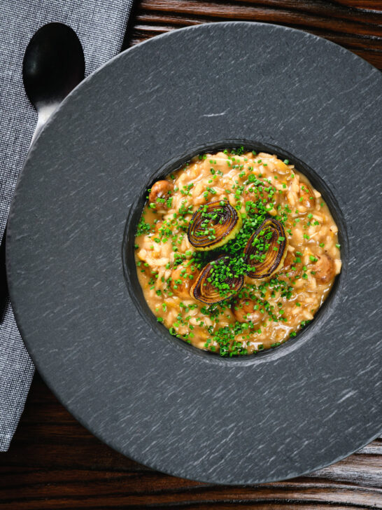 Overhead creamy balsamic leek and mushroom risotto topped with seared leek rings.