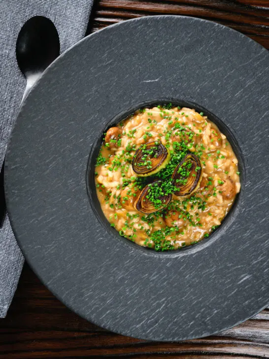 Overhead creamy balsamic leek and mushroom risotto topped with seared leek rings.