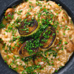 Close-up overhead creamy balsamic leek and mushroom risotto topped with seared leek rings.