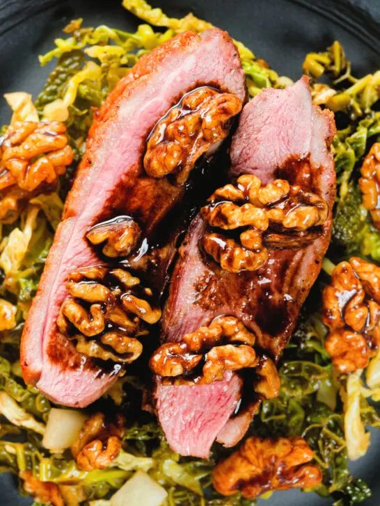 Close-up overhead balsamic and honey glazed duck breast with cabbage and walnuts.