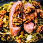 Close-up balsamic and honey glazed duck breast with cabbage and walnuts.