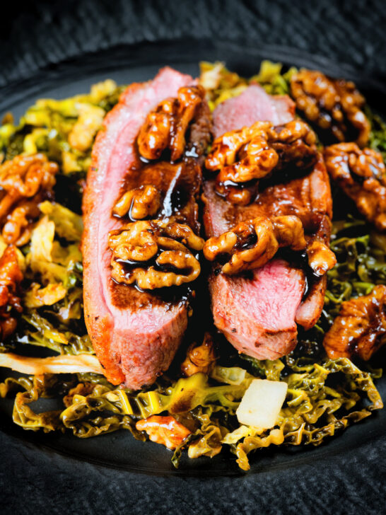 Close-up balsamic and honey glazed duck breast with cabbage and walnuts.