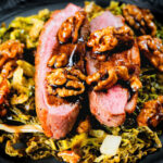 Close-up balsamic and honey glazed duck breast with cabbage and walnuts.