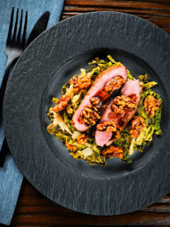 Overhead pan fried balsamic and honey glazed duck breast with cabbage and walnuts.