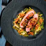 Overhead pan fried balsamic and honey glazed duck breast with cabbage and walnuts.