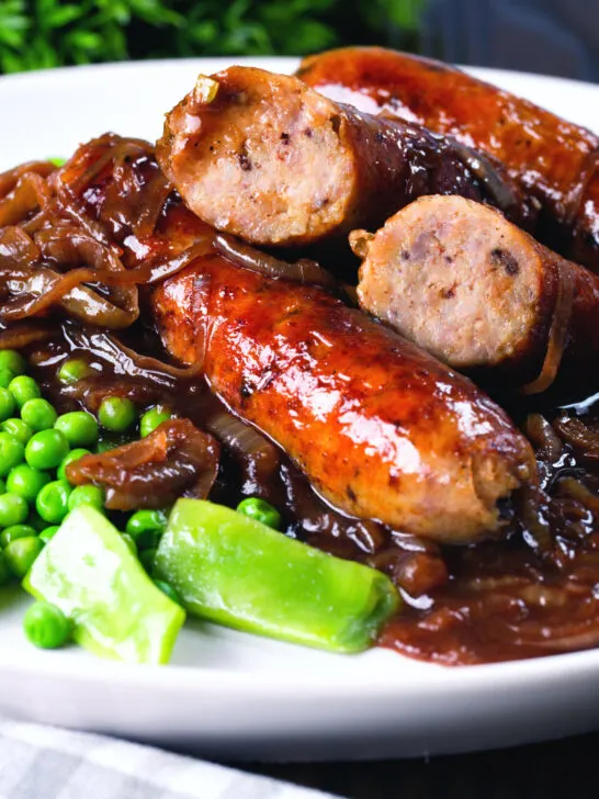 Close up bangers and mash with onion with cut uopen sausages showing cooked texture.