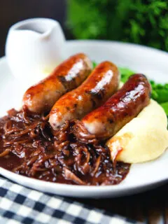 Bangers (sausages) and mash with onion gravy, peas and runner beans.