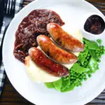 Overhead bangers (sausages) and mash with onion gravy, peas and runner beans.