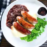 Overhead bangers (sausages) and mash with onion gravy, peas and runner beans.