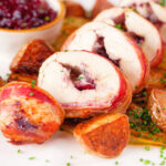 Carved cranberry and brie stuffed chicken wrapped in bacon with braised chicory and fried potatoes.