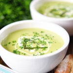 Cream of asparagus soup garnished with snipped chives, served with cheesy bread.