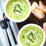 Overhead cream of asparagus soup garnished with snipped chives, served with cheesy bread.