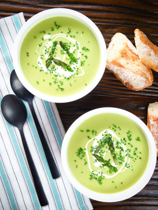 Overhead cream of asparagus soup garnished with snipped chives, served with cheesy bread.