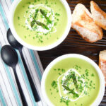 Overhead cream of asparagus soup garnished with snipped chives, served with cheesy bread.