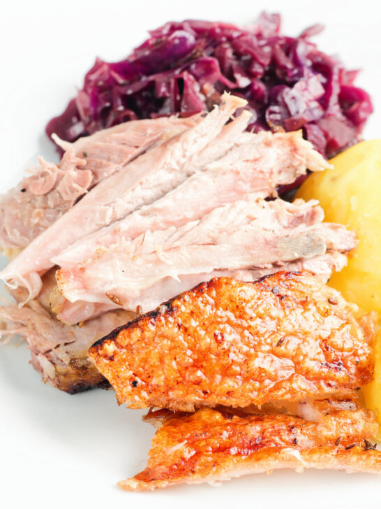 Meat and crackling from a beer roasted pork knuckle, served with potatoes and red cabbage.