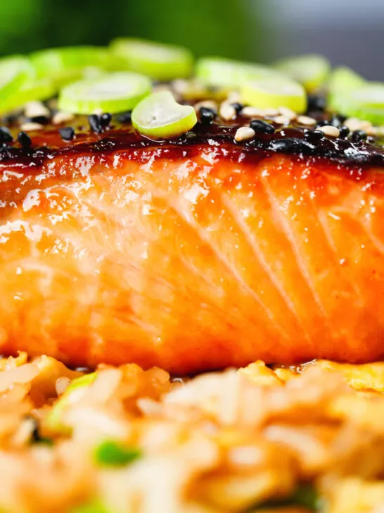 Close-up honey and miso glazed salmon garnished with sesame seeds and spring onions.