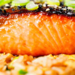 Close-up honey and miso glazed salmon garnished with sesame seeds and spring onions.