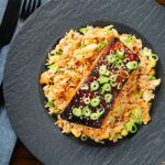 Overhead honey and miso glazed salmon with sesame seeds and spring onion served with egg fried rice.