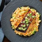 Overhead honey and miso glazed salmon with sesame seeds and spring onion served with egg fried rice.