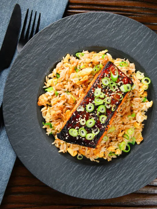 Overhead honey and miso glazed salmon with sesame seeds and spring onion served with egg fried rice.