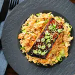 Overhead honey and miso glazed salmon with sesame seeds and spring onion served with egg fried rice.