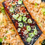 Overhead close-up honey and miso glazed salmon garnished with sesame seeds and spring onions.