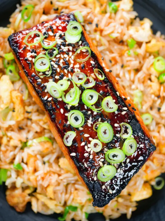 Overhead close-up honey and miso glazed salmon garnished with sesame seeds and spring onions.