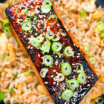 Overhead close-up honey and miso glazed salmon garnished with sesame seeds and spring onions.