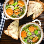 Overhead hotch potch soup or harvest broth with lamb and vegetables with buttered bread.
