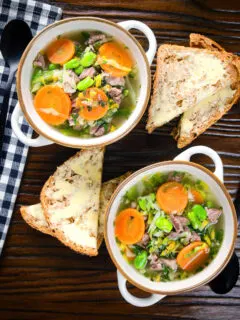 Overhead hotch potch soup or harvest broth with lamb and vegetables with buttered bread.