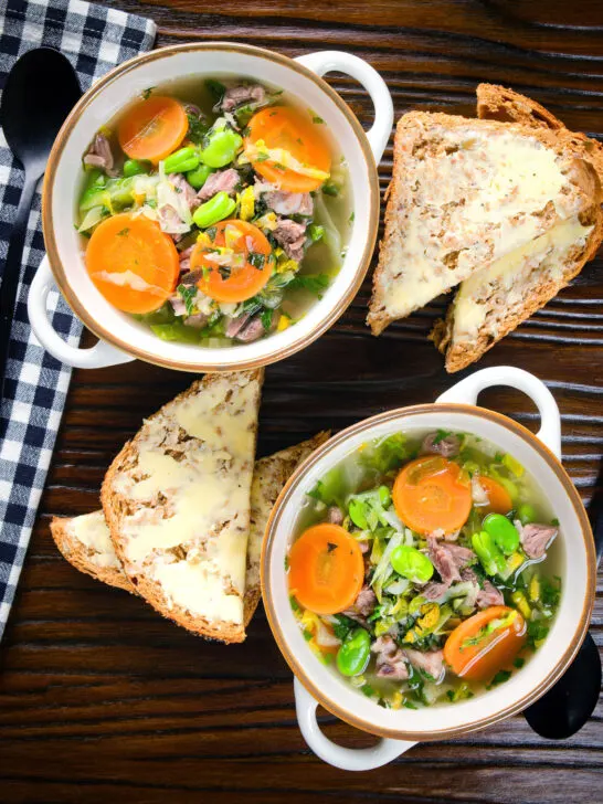 Overhead hotch potch soup or harvest broth with lamb and vegetables with buttered bread.