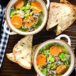 Overhead hotch potch soup or harvest broth with lamb and vegetables with buttered bread.