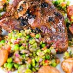 Close-up pan-fried leg of lamb steaks served with pea "salsa" and fried new potatoes.