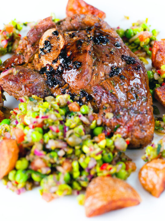 Close-up pan-fried leg of lamb steaks served with pea "salsa" and fried new potatoes.