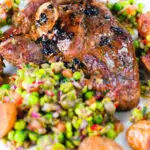 Close-up pan-fried leg of lamb steaks served with pea "salsa" and fried new potatoes.
