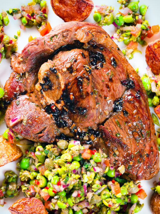Close-up overhead pan-fried leg of lamb steaks served with pea "salsa" and fried new potatoes.